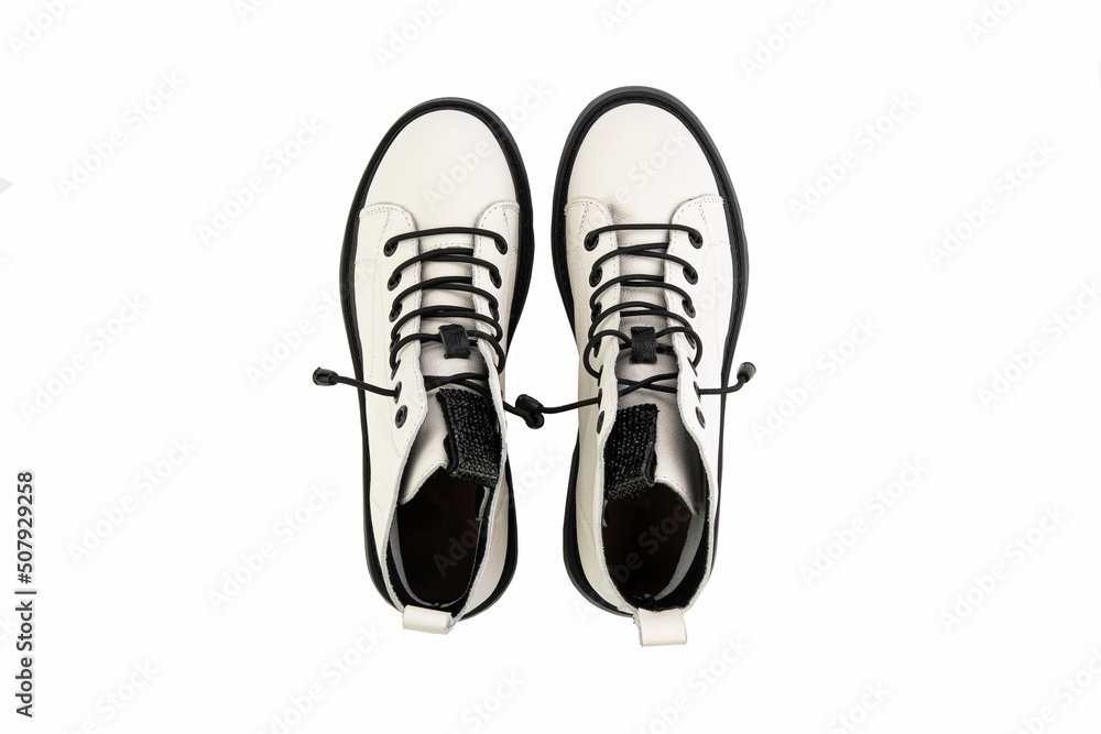 White leather ankle boots with black laces. Isolated close-up on white background. Top view. Casual seasonal shoes. Fashion shoes