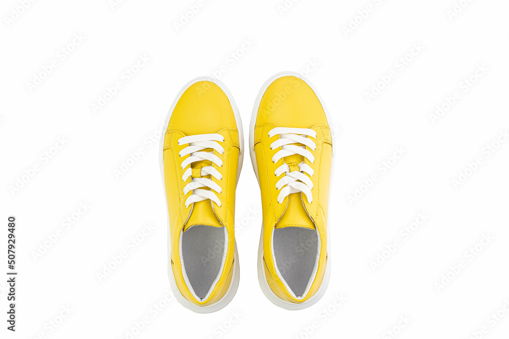Bright yellow leather sneakers. Casual women's style. White lacing and white rubber soles. Isolated close-up on white background. Top view. Fashion shoes.