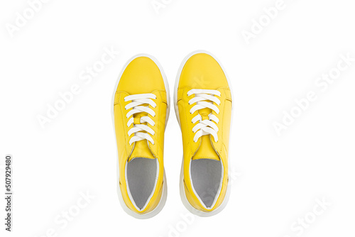 Bright yellow leather sneakers. Casual women's style. White lacing and white rubber soles. Isolated close-up on white background. Top view. Fashion shoes.