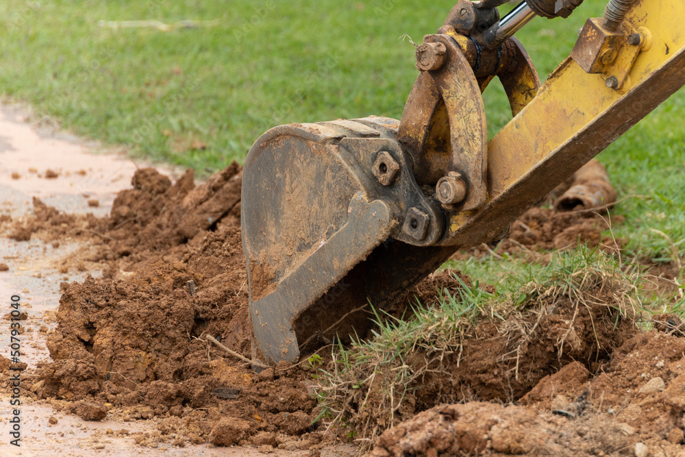 Excavator bucket with earth on asphalt. Excavation. Excavations with an excavator. Excavator bucket with earth on asphalt. Excavation. Excavations with an excavator.