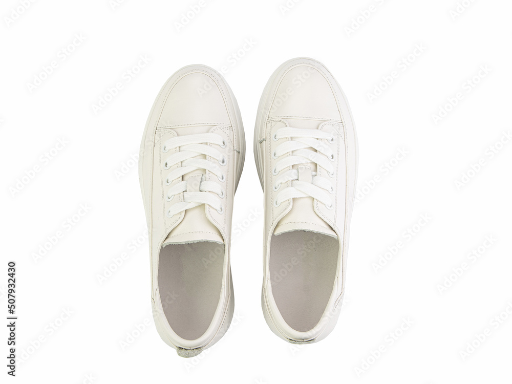White leather sneakers. Casual women's style. White lacing and white rubber soles. Isolated close-up on white background. Top view. Fashion shoes