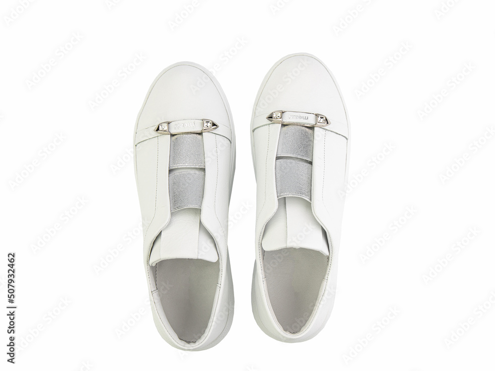White leather sneakers. Casual women's style. White lacing and white rubber soles. Isolated close-up on white background. Top view. Fashion shoes
