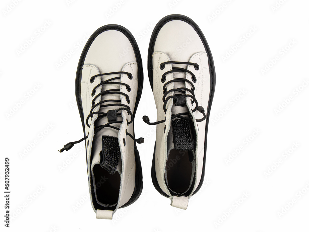 White leather ankle boots with black laces. Isolated close-up on white background. Top view. Casual seasonal shoes. Fashion shoes