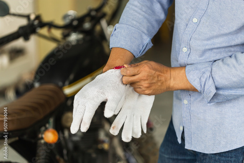 Mechanic wears gloves fixing motorbike in workshop garage, Man repairing motorcycle in repair shop, Repairing and maintenance concepts