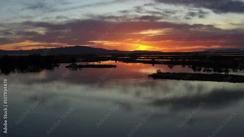 Drone Aerial Descending on Lake at Sunset With Sun Reflecting on Water Surface Drone Aerial Descending on Lake at Sunset With Sun Reflecting on Water Surface
