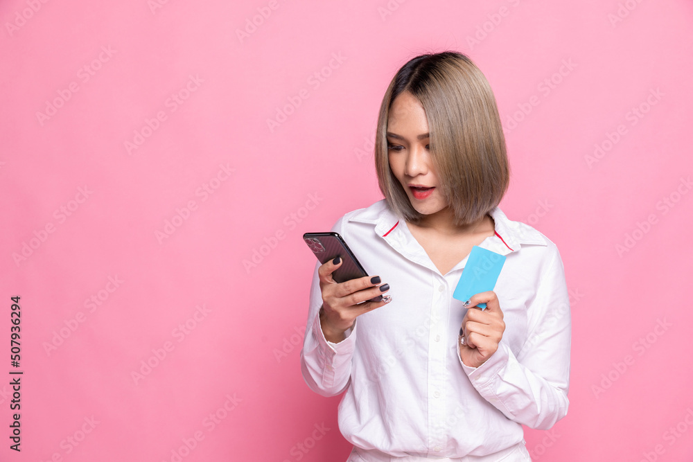 Portrait of a young asian woman showing credit card and mobile phone isolated over pink background. Portrait of a young asian woman showing credit card and mobile phone isolated over pink background.