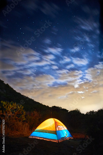camping tent in the darkness with blue sky and clouds in front of a mountain, vertical picture in san miguel de allende guanajuato 