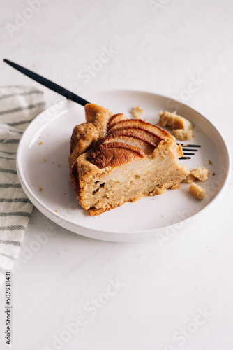 A slice of an apple cake served in a white plate.