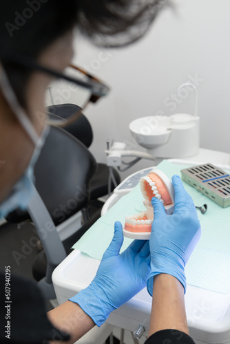 gloved hand showing the bite of an artificial prosthesis, detail of teeth, molars, gums and smile design, dentist tool, studio