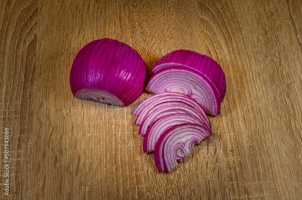 a peeled red onion cut into two halves, one half whole but peeled upside down showing the purple