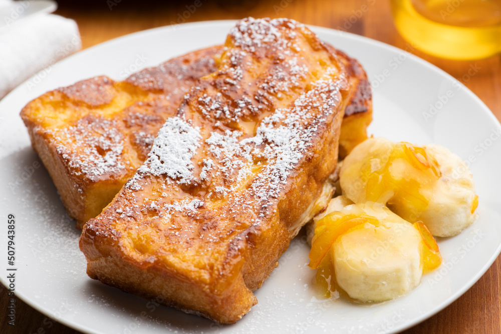朝食のテーブルの上にバナナとオレンジマーマレードを添えたカリカリ食感のキャラメルフレンチトースト