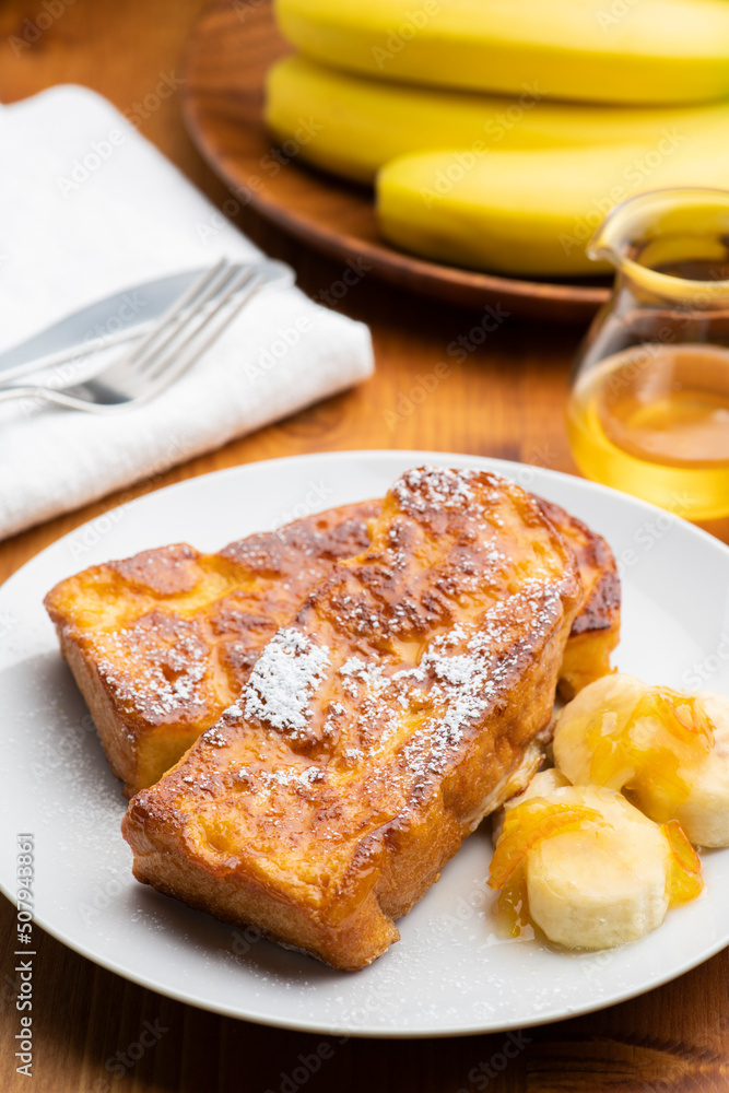 朝食のテーブルの上にバナナとオレンジマーマレードを添えたカリカリ食感のキャラメルフレンチトースト