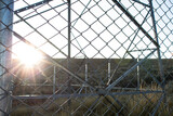 Enclosed - metal bars - sunset sun - dry and arid place - prison
