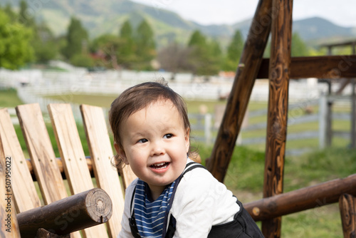 木のベンチの上で微笑むハーフの男の子 © 理絵 ジュト