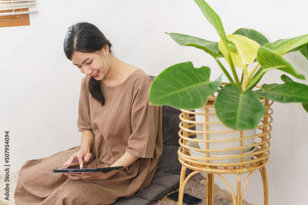 Relaxation lifestyle concept, Young Asian woman using tablet to surf social media in living room