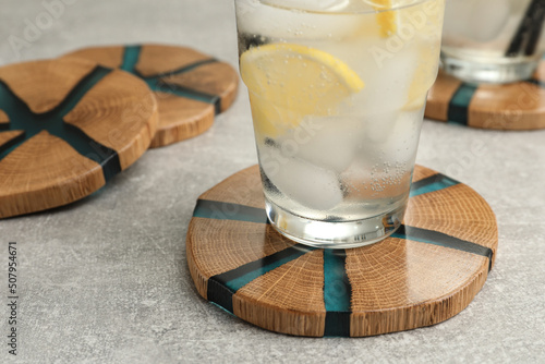 Cocktail and stylish cup wooden coasters on light grey table