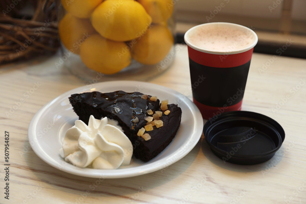 Tasty coffee in takeaway paper cup and dessert on wooden table indoors Tasty coffee in takeaway paper cup and dessert on wooden table indoors