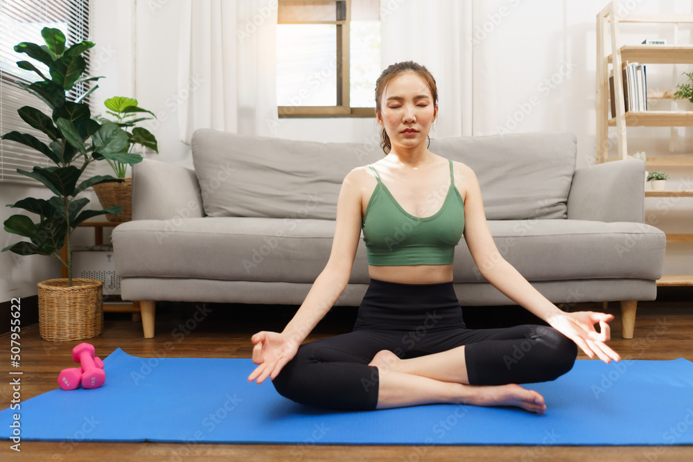 Yoga and wellness concept, Young Asian woman doing yoga with meditation in padmasana or lotus pose Yoga and wellness concept, Young Asian woman doing yoga with meditation in padmasana or lotus pose