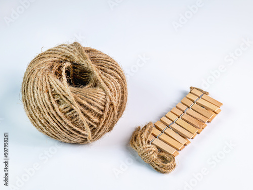 coiled raw rope Made of various fibers into a long rope. Empty with a small clip made of wood. For brown crafts, white background isolated, studio shot.