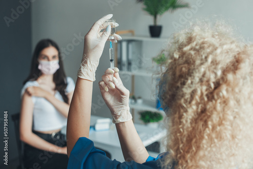 Nurse in white gloves holding, covid-19 vaccine disease preparing for human. Doctor preparing a dose for a patient of the third vaccine for Covid-19