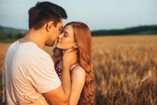 Caucasian couple kissing in the field of wheat on sunny summer day. Wheat field. Sunny day.