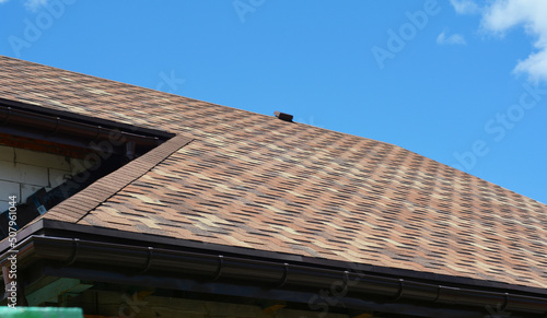 Close up on asphalt shingles roofing construction. House asphalt shingles roofing construction waterproofing with vent on rooftop.
