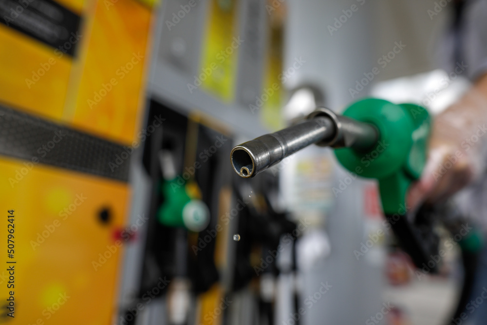 Shallow depth of field (selective focus) details with a man holding a fuel pump dripping with gasoline in a gas station. Shallow depth of field (selective focus) details with a man holding a fuel pump dripping with gasoline in a gas station.