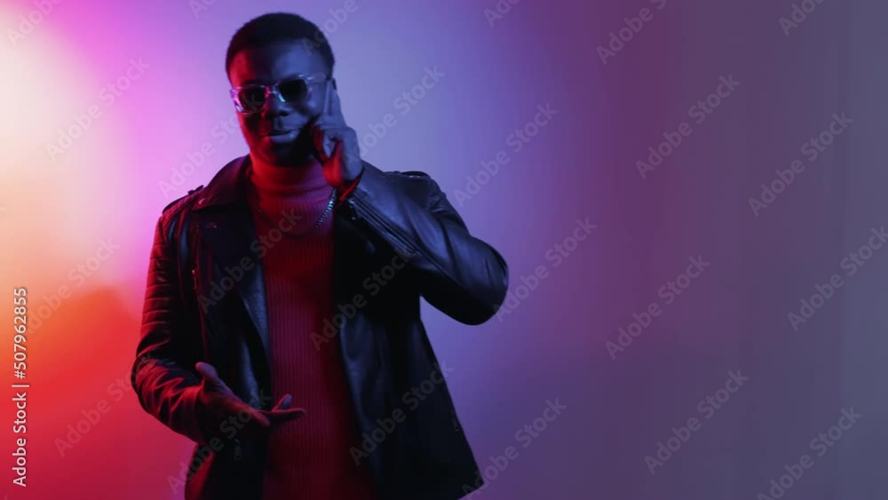 Mobile communication. Phone entertainment. Millennial lifestyle. Gadget ad. Joyful man talking on cell at bright neon light empty space gradient background. Mobile communication. Phone entertainment. Millennial lifestyle. Gadget ad. Joyful man talking on cell at bright neon light empty space gradient background.