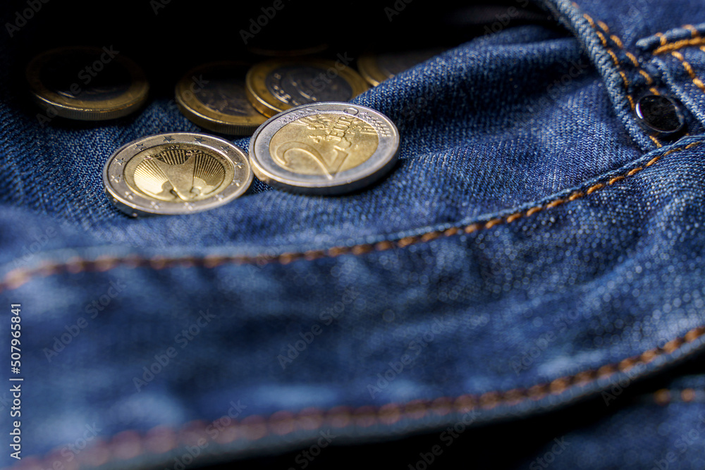 Symbol for crisis or cost of living or bankruptcy. Coins of one and two euros spilling out of an inside-out jeans pocket Symbol for crisis or cost of living or bankruptcy. Coins of one and two euros spilling out of an inside-out jeans pocket