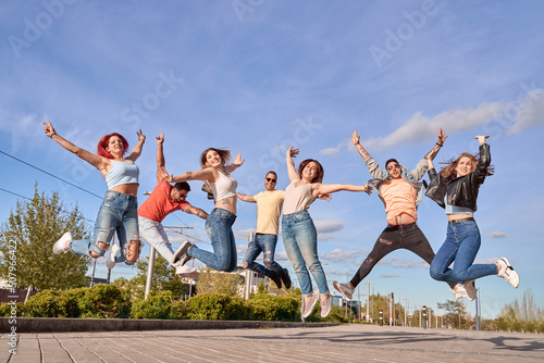 Group of happy friends smiling at camera while jumping together outdoors. Friendship and happiness concept.