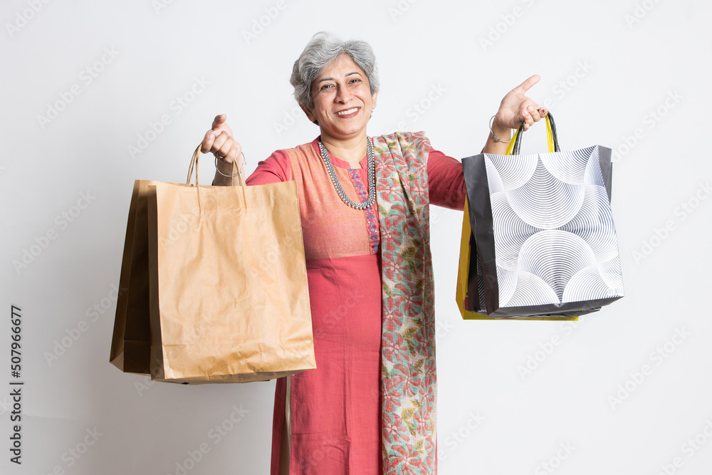 Happy excited indian senior mature woman holding shopping bags. elderly  female shopper wearing traditional outfit, isolated white studio  background, black Friday deal, diwali festive discount sale. Photos | Adobe  Stock