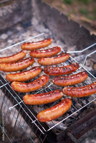 Tasty Sausages grilling on charcoal grill grate