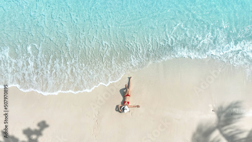 Aerial view of woman body in bikini sunbathing as laying on the  beach, blue sea water in background -Summer fashion concept photo