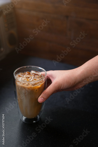 Ice coffee on a table with cream being poured into it showing the texture and refreshing look of the drink