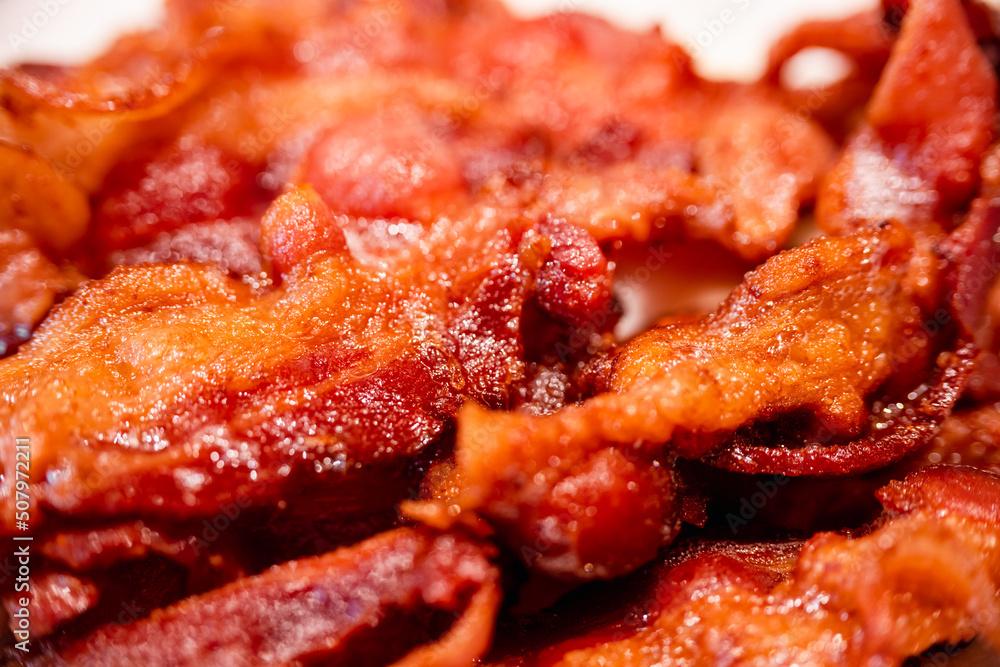 Macro view of appetizing, tasty, fried, crispy bacon slices, close-up, meat ham to scrambled eggs, shallow depth of field Macro view of appetizing, tasty, fried, crispy bacon slices, close-up, meat ham to scrambled eggs, shallow depth of field