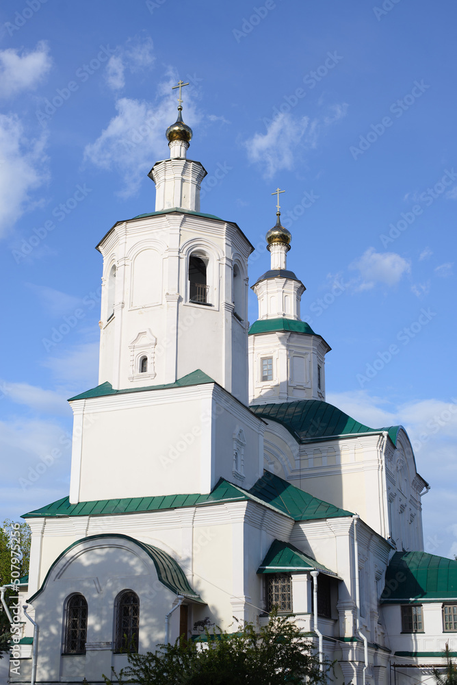 Ancient white monastery, church with crosses facade against blue sky outdoors. Close-up religious architecture of Middle Ages