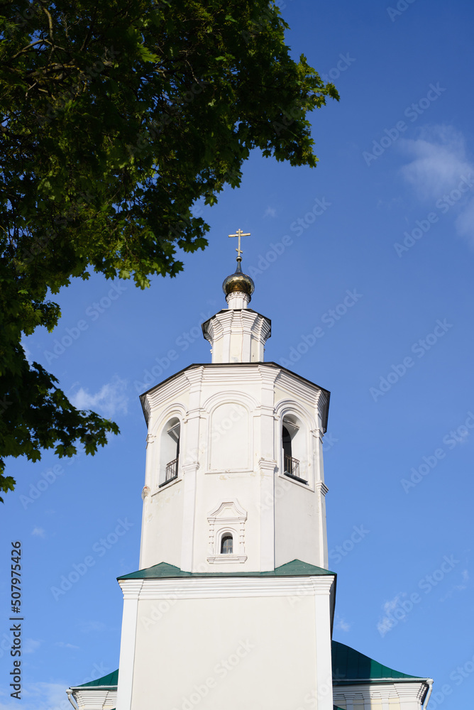 Ancient white church with cross against blue sky, old monastery facade outdoors, close-up