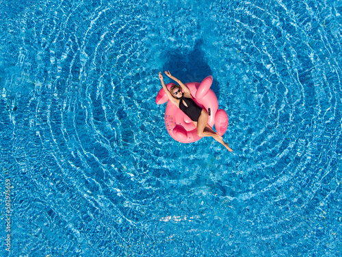 Aerial drone view of woman on flamingo pool float in sea. Summer holidays, enjoying summer vacations during quarantine.