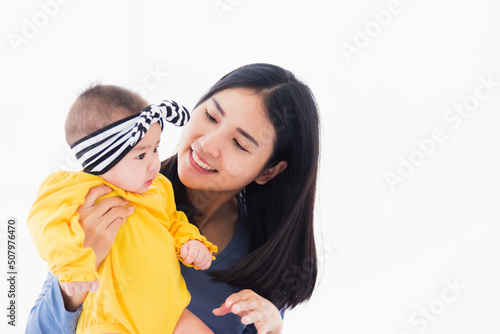 Portrait of beautiful young Asian mother playing and smiling together with his newborn little baby at home, Parent mom and little kid relaxing in the bedroom, Family having fun together