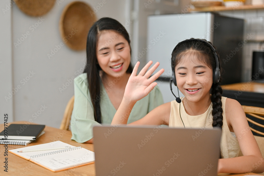 Pretty Asian young little girl having an online class, learning on laptop Pretty Asian young little girl having an online class, learning on laptop