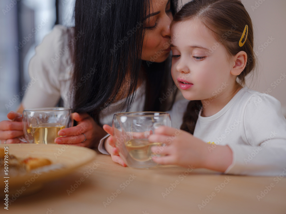 Family drinking tea with cookies on kitchen at home. Mother and daughter having fun, happy moment together at home. Family drinking tea with cookies on kitchen at home. Mother and daughter having fun, happy moment together at home.