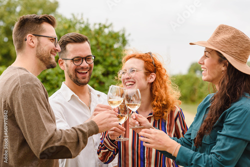 Happy friends having fun drinking wine at winery vineyard - Friendship concept with young people enjoying harvest time together