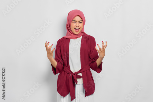 Angry beautiful Asian woman in casual shirt screaming out loud  expressing negative emotions isolated over white background