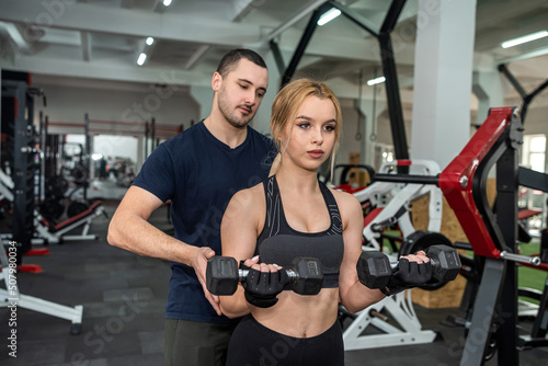 Beautiful young couple of man and woman are training in the gym to keep fit.