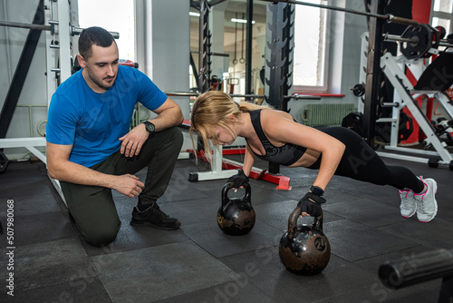 female client and the trainer work out according to an individual program together in the gym