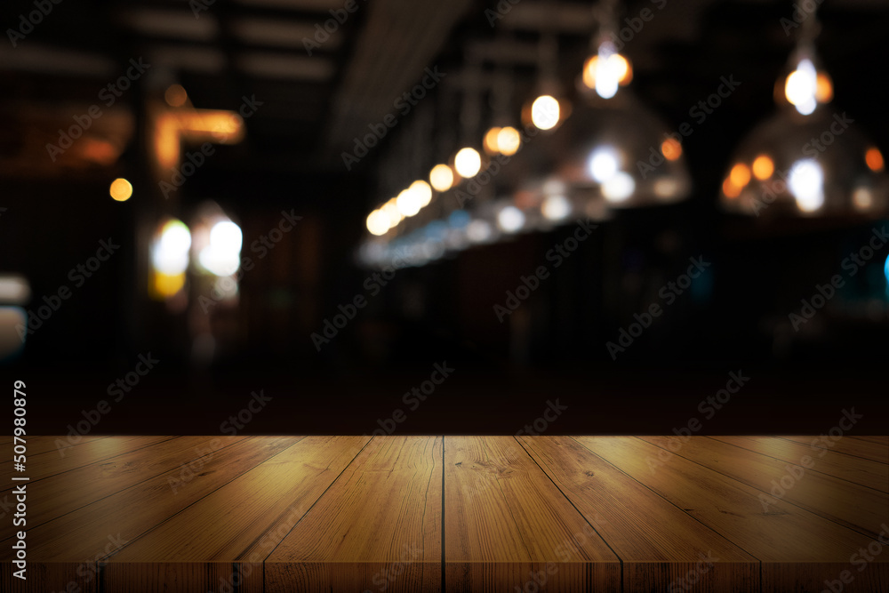 Empty wooden table top with blurred coffee shop or restaurant interior background.