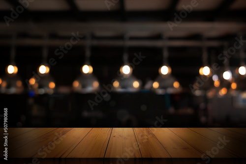 Empty wooden table top with blurred coffee shop or restaurant interior background.