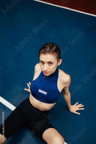 Beautiful sports woman in sportswear lies on the sports field and rests after training.Vertical