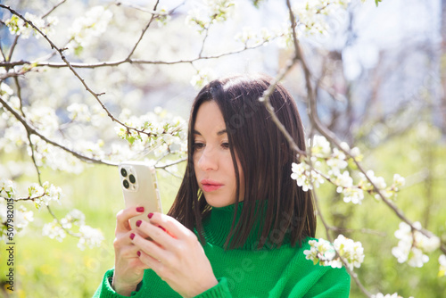 Spring awakening. Slow life. Enjoying the little things. Dreaming of spring. a woman uses smartphone in a spring flowering garden. social networks