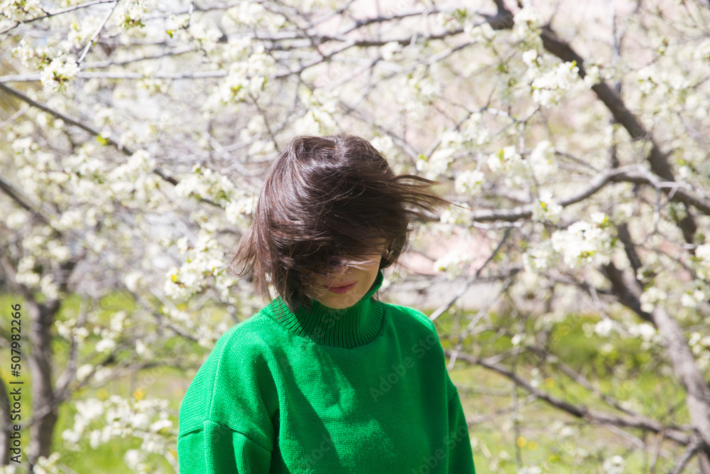 woman in green sweater with short hair blowing in the wind in flowering spring garden. Spring awakening. Slow life. Enjoying the little things. Dreaming of spring. woman in green sweater with short hair blowing in the wind in flowering spring garden. Spring awakening. Slow life. Enjoying the little things. Dreaming of spring.